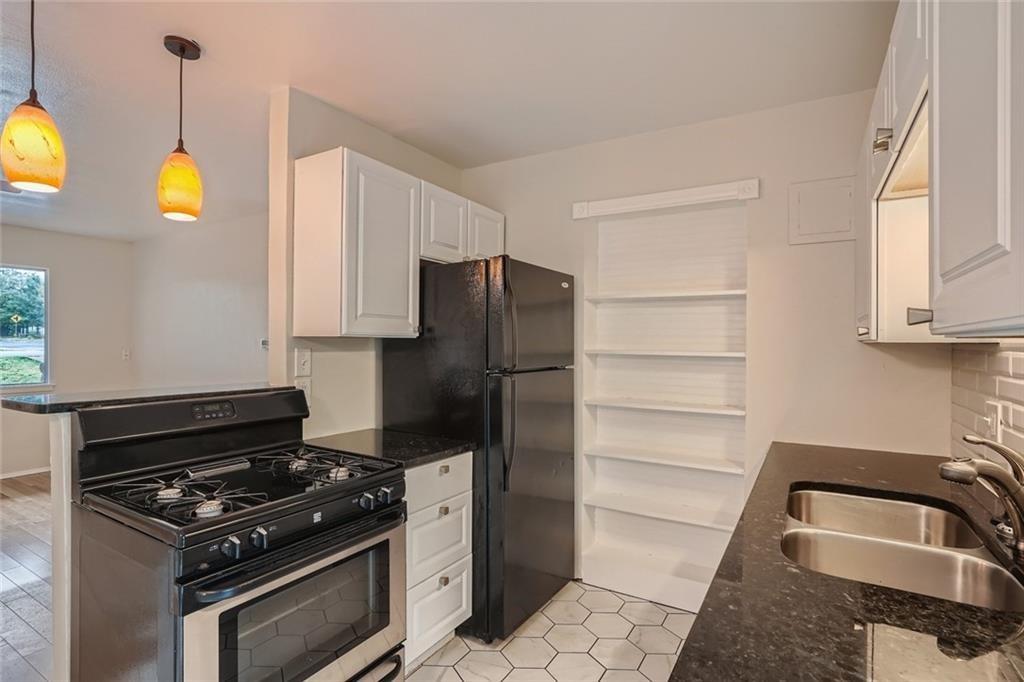 2101 Wheless Lane, Unit A Austin, TX 78723 - Photo 4 of 11 Kitchen with gas range, dark stone counters, white cabinetry, decorative light fixtures, and tasteful backsplash