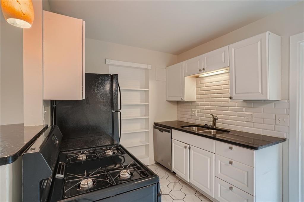 2101 Wheless Lane, Unit A Austin, TX 78723 - Photo 5 of 11 Kitchen with black appliances, white cabinets, dark stone counters, backsplash, and light tile patterned floors