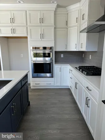 a kitchen with a sink dishwasher and white cabinets with wooden floor