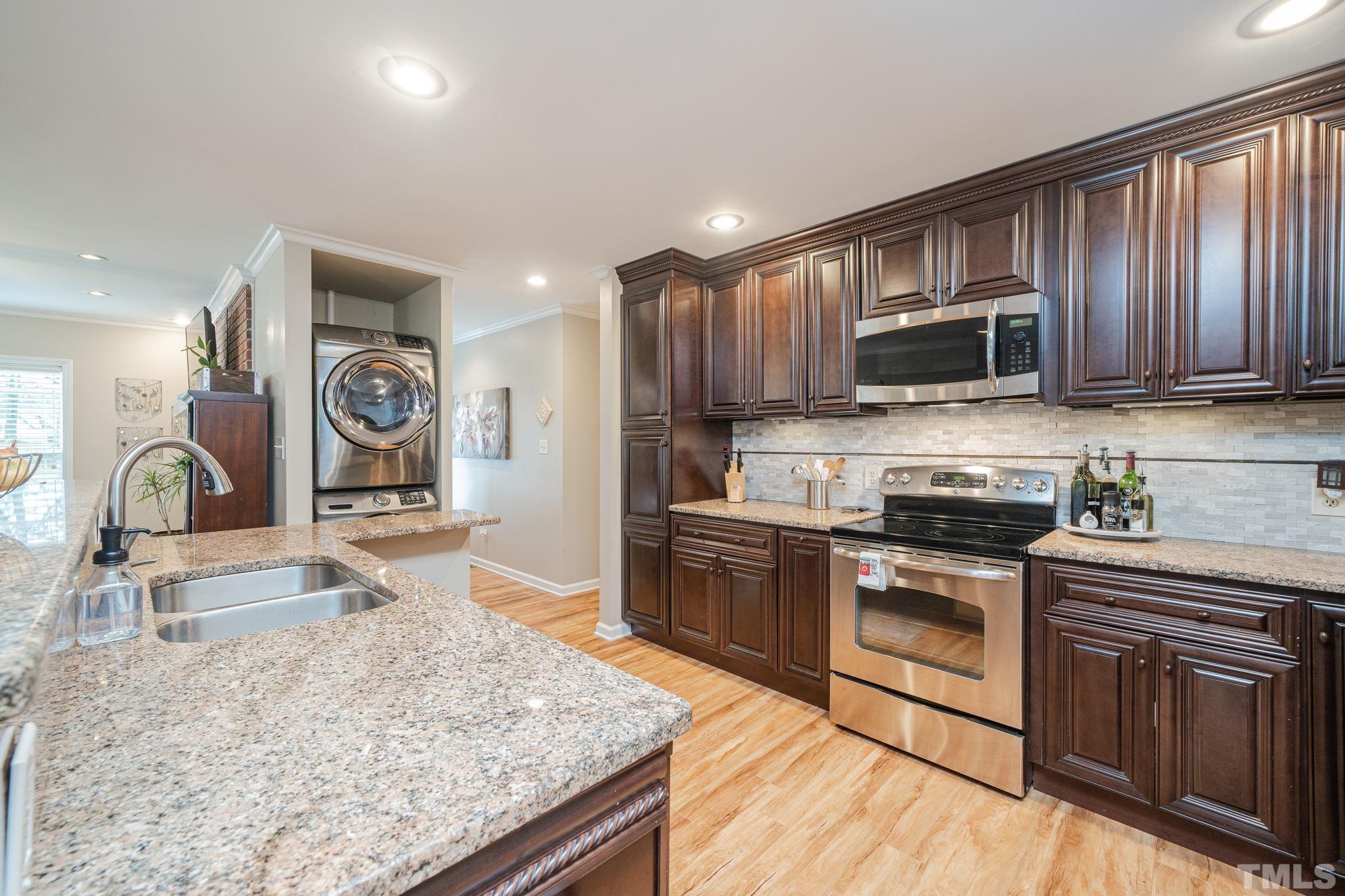 10104 Jordan Road Raleigh, NC 27603 - Photo 13 of 26 a kitchen with stainless steel appliances granite countertop a stove top oven a sink dishwasher a dining table and chairs with wooden floor