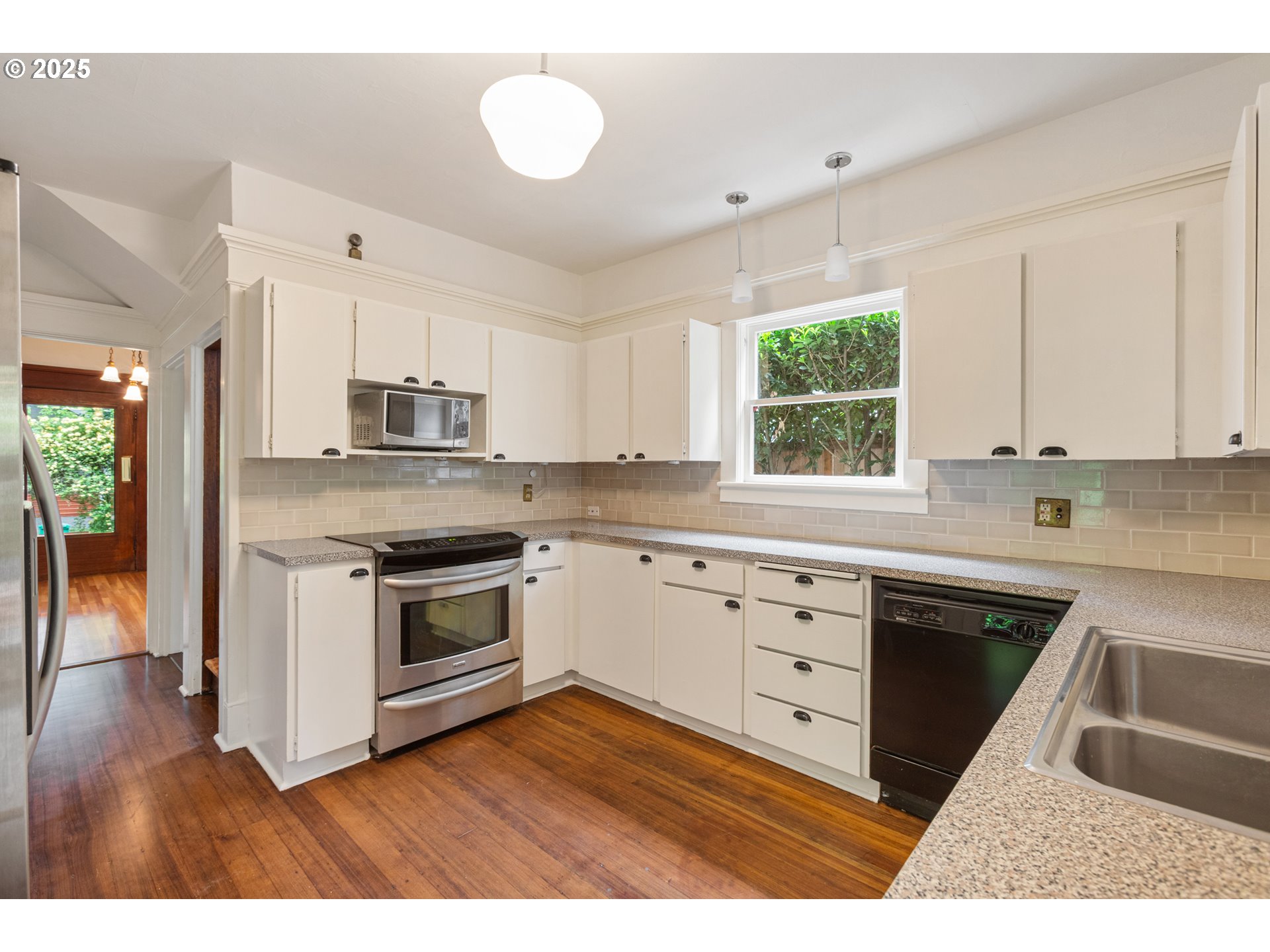 2404 Northeast 47th Avenue Portland, OR 97213 - Photo 14 of 35 a kitchen with stainless steel appliances granite countertop a stove a sink dishwasher and white cabinets with wooden floor
