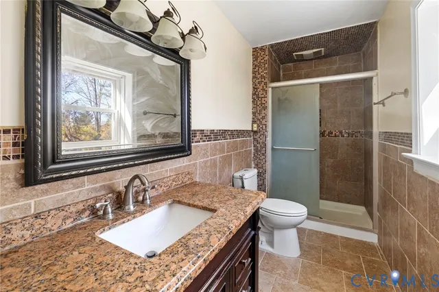 a bathroom with a granite countertop sink toilet and shower