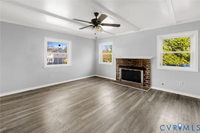 an empty room with windows fireplace and wooden floor