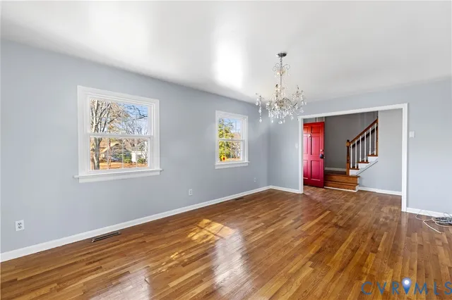 a view of an empty room with window and wooden floor