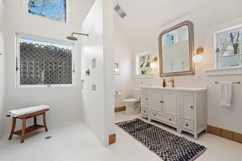 a bathroom with a toilet a sink a mirror and a shower