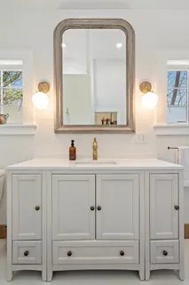 a bathroom with white cabinets and a mirror