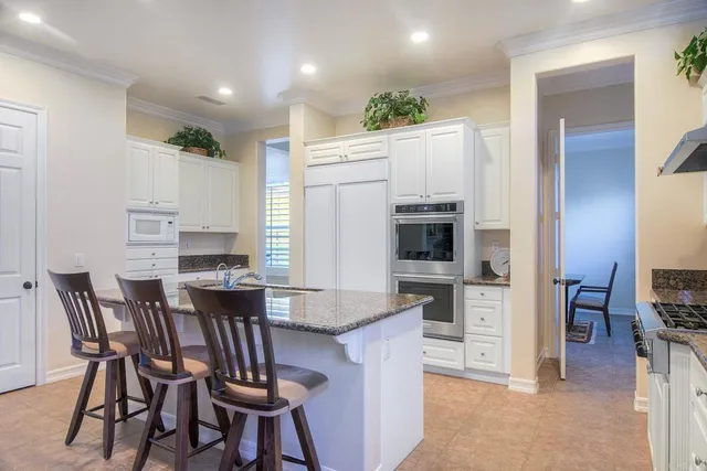 a kitchen with stainless steel appliances kitchen island granite countertop a table chairs and a refrigerator