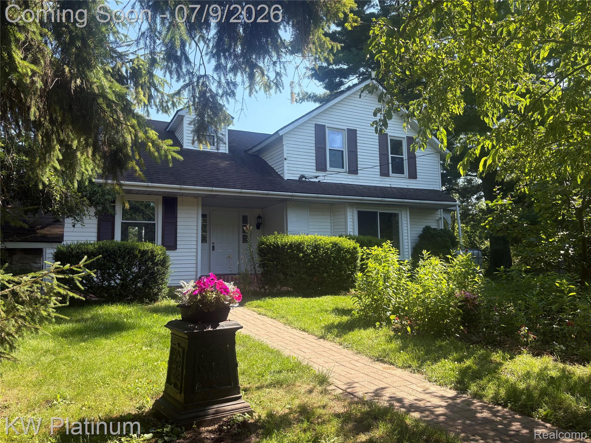 7280 North Road Fort Gratiot, MI 48059 - Photo 1 of 40 White siding exterior featuring window shutters, multiple dormer windows, a black shingle roof, and a stone-paver walkway