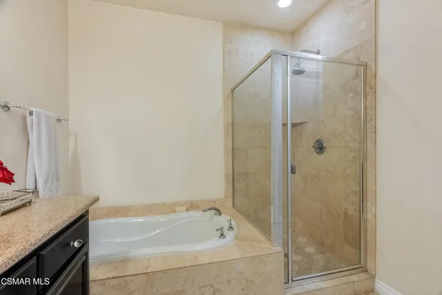 a bathroom with a granite countertop bathtub shower sink and vanity