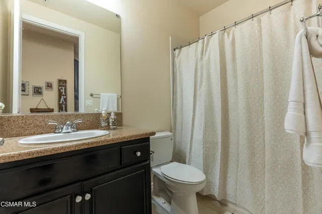 a bathroom with a granite countertop sink toilet and a mirror