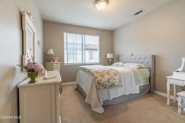 a bedroom with a bed table flowerpot and window