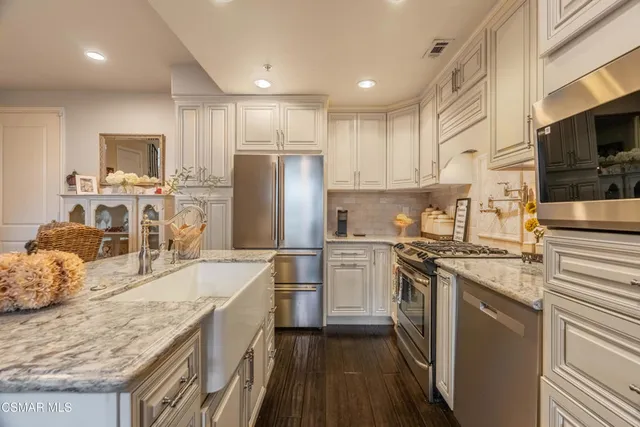 a kitchen with stainless steel appliances granite countertop a sink stove microwave and refrigerator