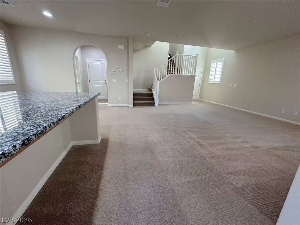 146 Tree Shot Court Las Vegas, NV 89113 - Photo 5 of 18 A spacious, naturally illuminated room featuring a granite countertop, carpeted flooring, and a staircase leading to the second level.