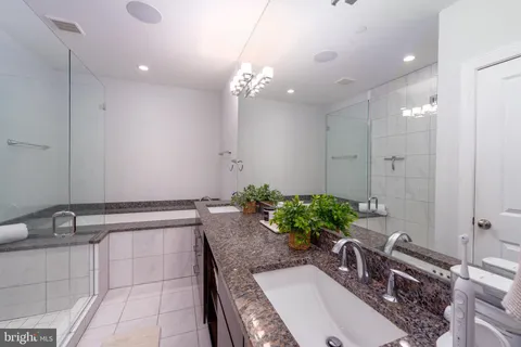 a bathroom with a granite countertop bathtub a sink and a potted plant