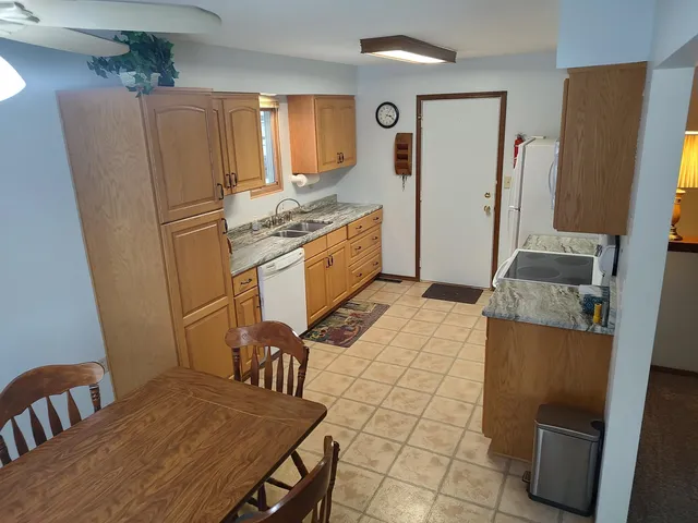 a kitchen with stainless steel appliances granite countertop a refrigerator a stove a sink dishwasher and white countertops with wooden floor