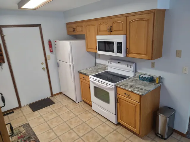 a kitchen with stainless steel appliances granite countertop a table chairs and a refrigerator