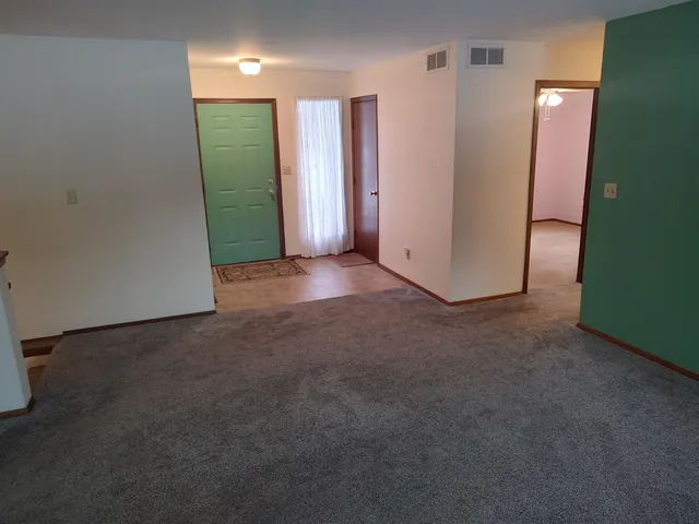 an empty room with a chandelier fan and windows