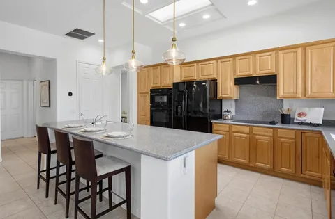 a kitchen with stainless steel appliances kitchen island granite countertop a table chairs in it and wooden floors