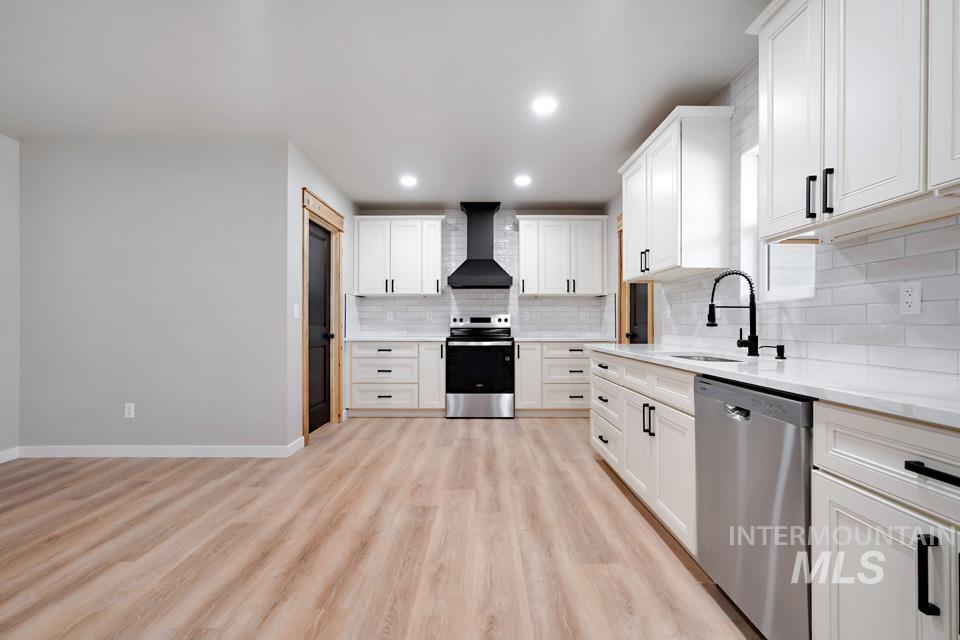 535 Day Road Weiser, ID 83672 - Photo 12 of 44 Kitchen with stainless steel appliances, white cabinetry, light wood-style flooring, light stone counters, and tasteful backsplash