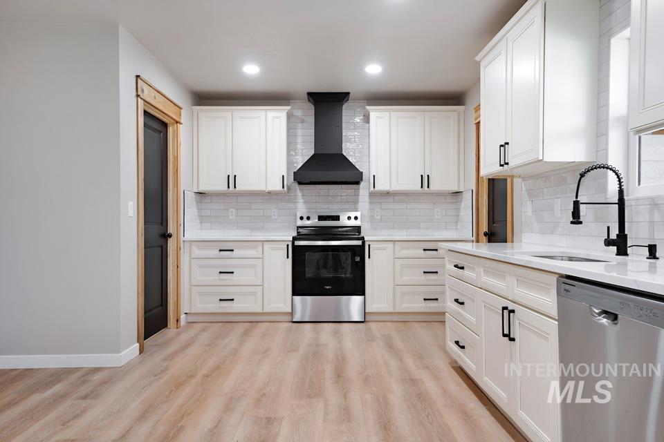 535 Day Road Weiser, ID 83672 - Photo 16 of 44 Kitchen featuring stainless steel appliances, white cabinets, light wood-type flooring, light stone counters, and decorative backsplash