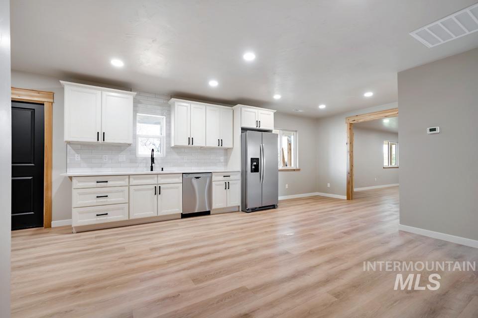 535 Day Road Weiser, ID 83672 - Photo 19 of 44 Kitchen with stainless steel appliances, white cabinetry, decorative backsplash, light wood-style floors, and recessed lighting
