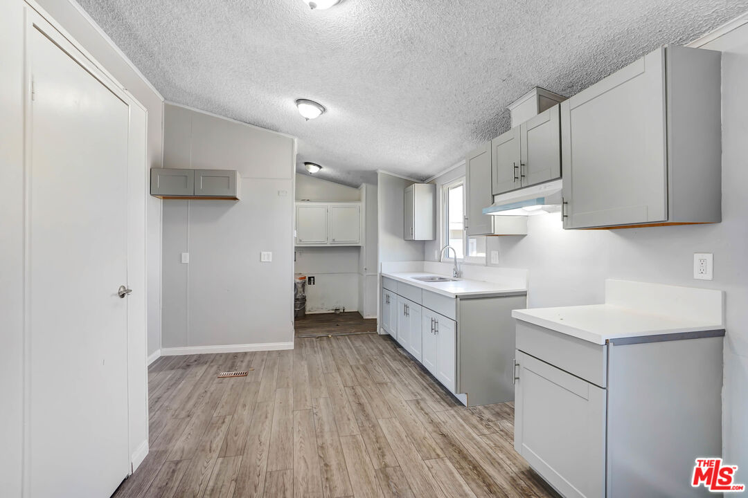 11351 Eaby Road Phelan, CA 92371 - Photo 5 of 23 a kitchen with a sink a refrigerator and wooden cabinets