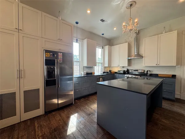 a kitchen with granite countertop a refrigerator a sink dishwasher a stove and white cabinets with wooden floor