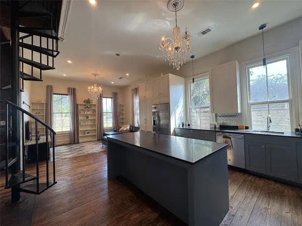 a large kitchen with granite countertop a stove a sink a dishwasher and a dining table with wooden floor