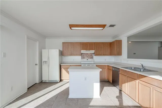 a kitchen with stainless steel appliances a sink a stove a refrigerator and cabinets