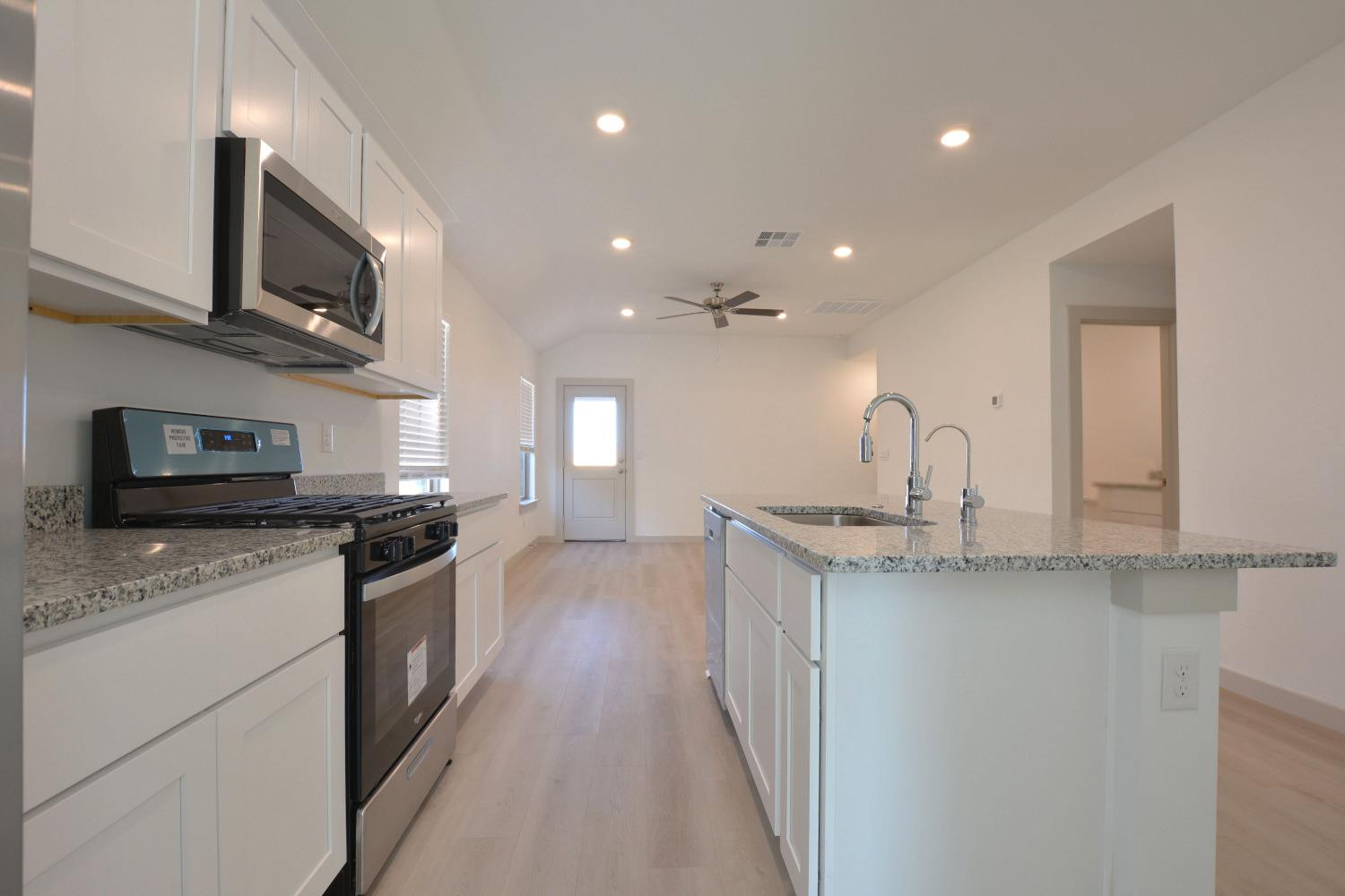 7438 8th Street Lubbock, TX 79416 - Photo 5 of 18 a kitchen with stainless steel appliances granite countertop a sink a stove top oven a granite counter space and cabinets