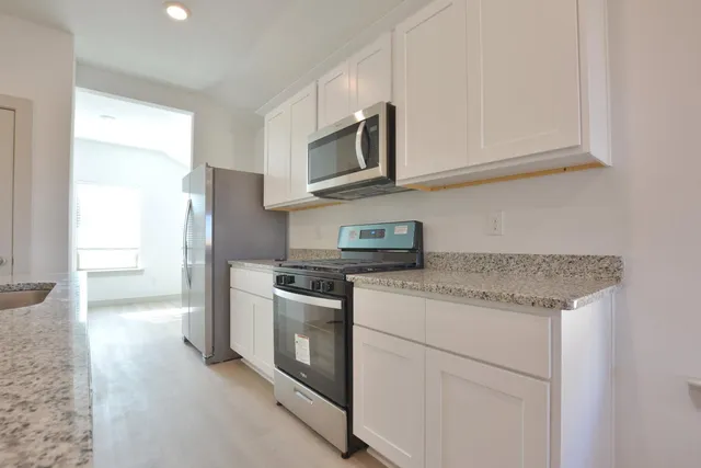 a kitchen with stainless steel appliances granite countertop white cabinets and a granite counter tops