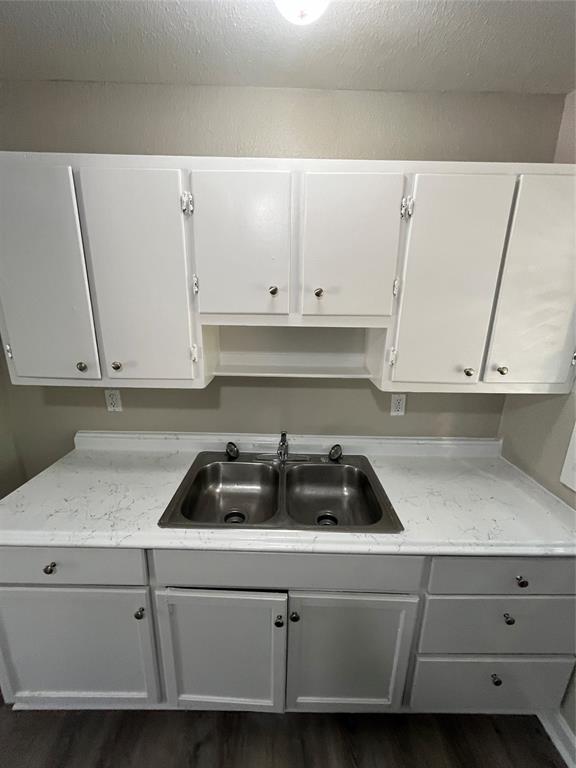 1622 Centerville Road Dallas, TX 75228 - Photo 9 of 19 Galley kitchen with white cabinetry, stainless steel double basin sink, light-toned countertops, and wood-finish flooring