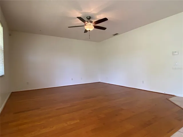 an empty room with wooden floor and a ceiling fan