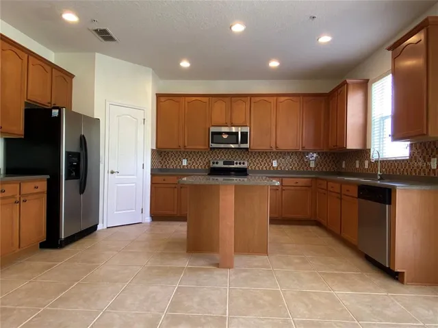a kitchen with stainless steel appliances granite countertop a stove a sink and a refrigerator