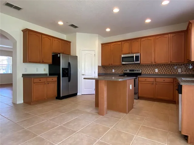 a kitchen with stainless steel appliances granite countertop a stove a sink and a refrigerator