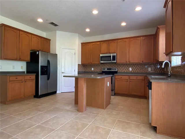 a kitchen with stainless steel appliances granite countertop a stove a sink and a refrigerator