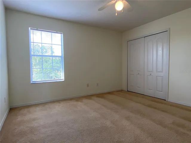 an empty room with a window and a chandelier fan