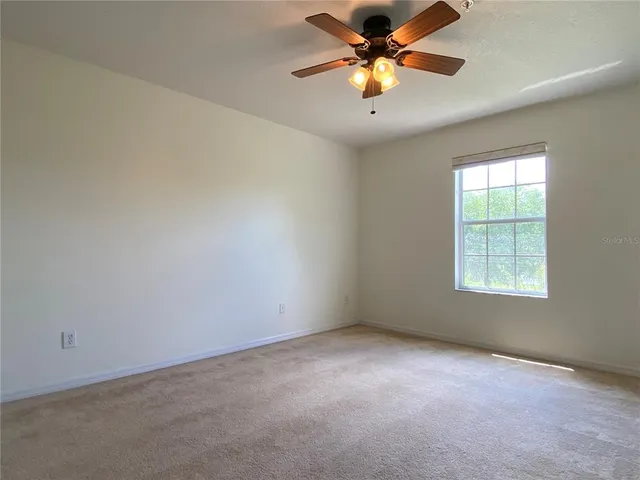 an empty room with a window and a fan