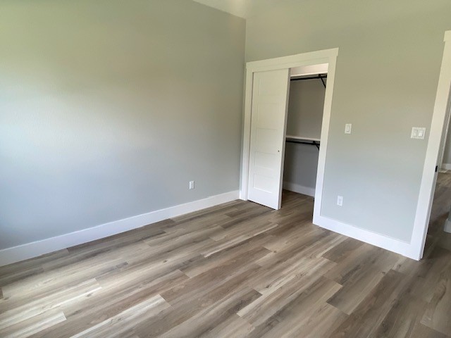 116 Field Street Luling, TX 78648 - Photo 23 of 33 A well-lit bedroom featuring durable plank flooring and a convenient sliding closet door.