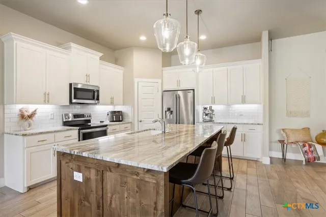 a kitchen with stainless steel appliances granite countertop a dining table chairs refrigerator and microwave