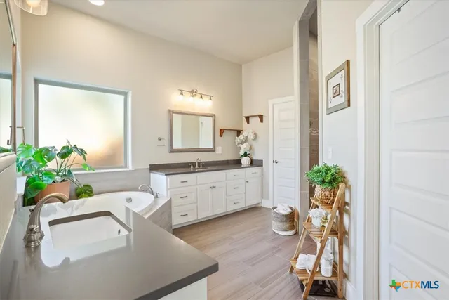 a spacious bathroom with a granite countertop sink a mirror a vanity and a window