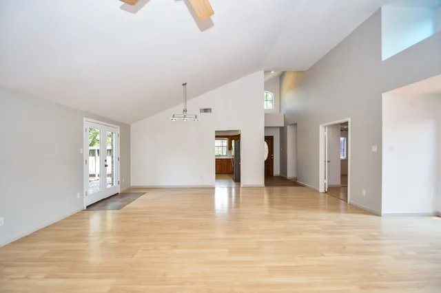 a view of an empty room with window and wooden floor