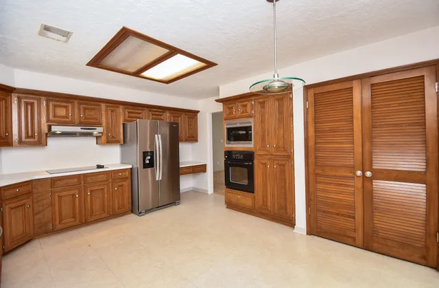 a large kitchen with stainless steel appliances granite countertop a refrigerator and a sink