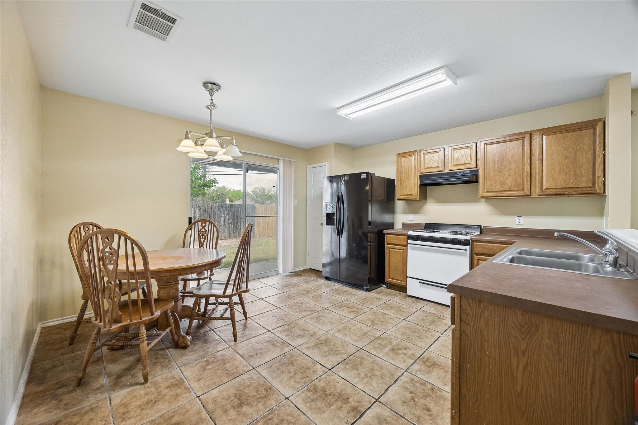 14410 Sandifer Street Austin, TX 78725 - Photo 5 of 10 a kitchen with stainless steel appliances a refrigerator a stove a sink dishwasher a dining table and chairs with wooden floor