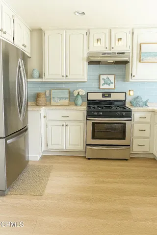 a kitchen with stainless steel appliances granite countertop a stove a refrigerator and a white cabinets