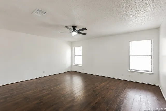 an empty room with wooden floor and windows