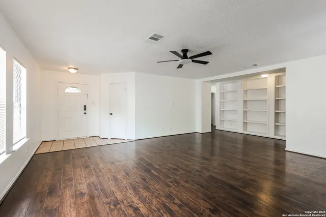 a view of an empty room with a window and wooden floor