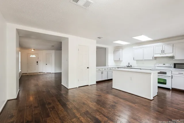 a kitchen with a refrigerator and white cabinets