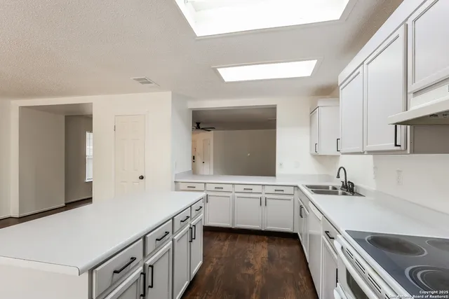 a kitchen with a sink stove top oven and cabinets
