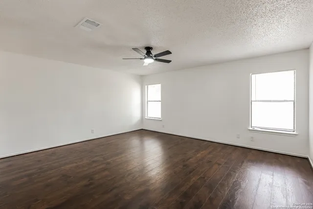 an empty room with wooden floor and windows